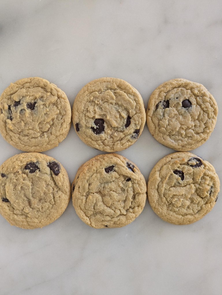 Six chocolate chip cookies arranged on marble
