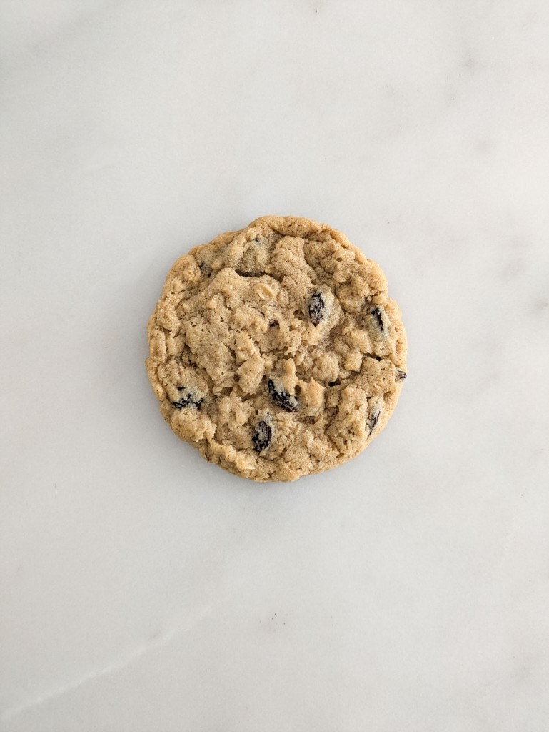 A single oatmeal raisin cookie on marble