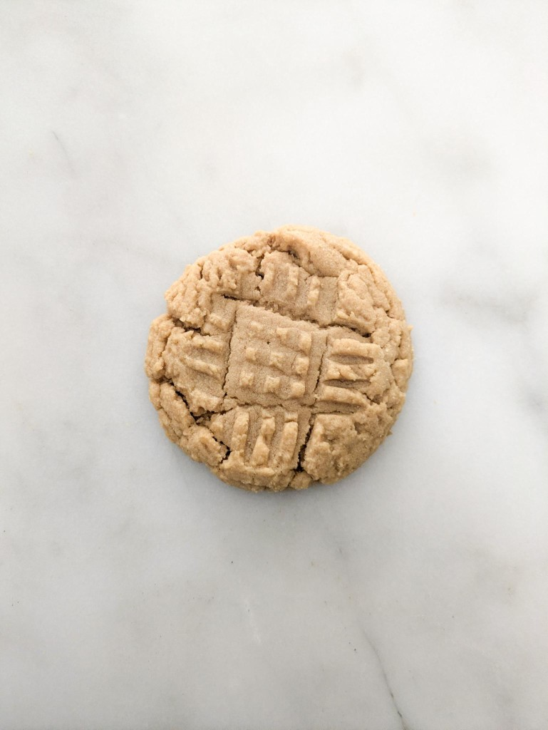 A single peanut butter cookie on marble